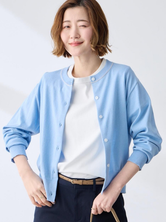 サックスのファンクションクルーネックカーディガン・ホワイトのトップス・ネイビーのパンツを着用した女性