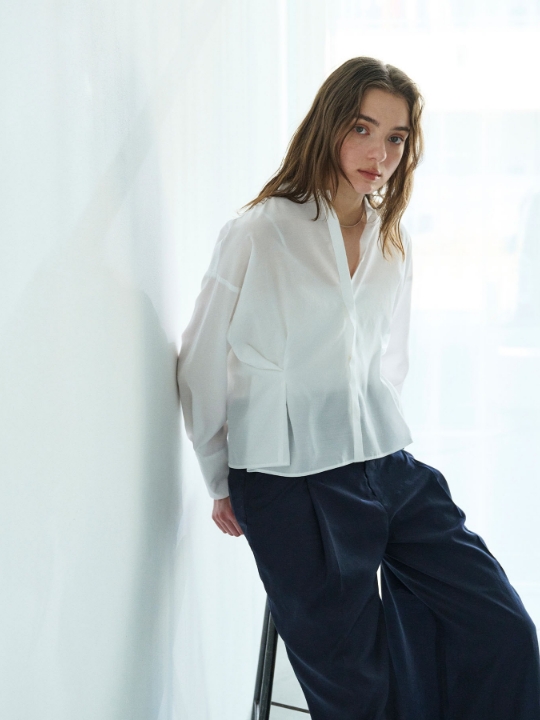 ホワイトのブライトローン撥水フォルムブラウス【AIRY MOTION】・ネイビーのパンツを着用した女性