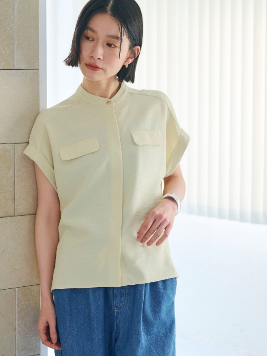 オフベージュのサマナチュラバンドカラーブラウス・オフベージュのパンツを着用した女性