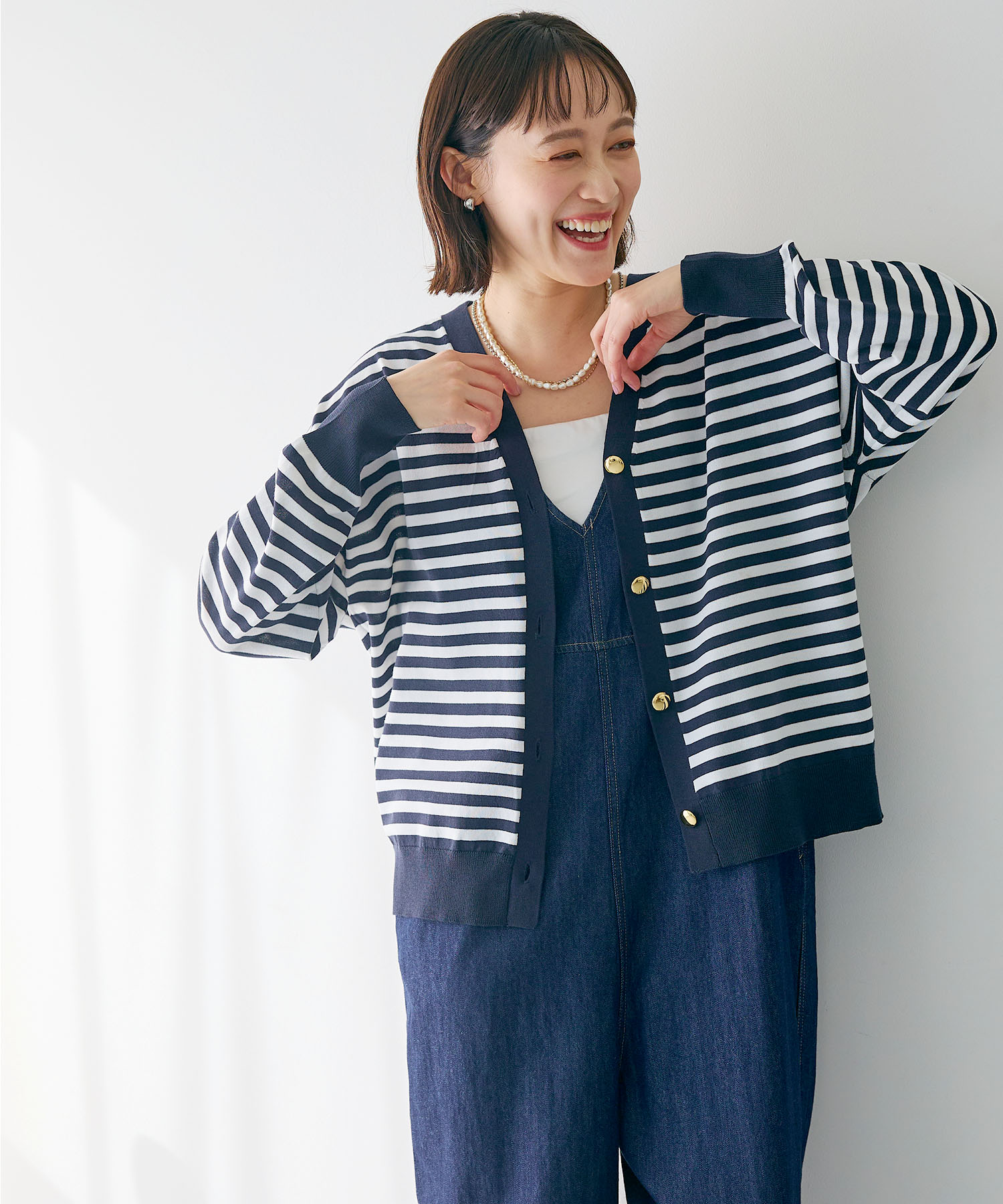 CROSS FUNCTION 《洗える》金釦ボーダーVネックカーディガンを着用した女性