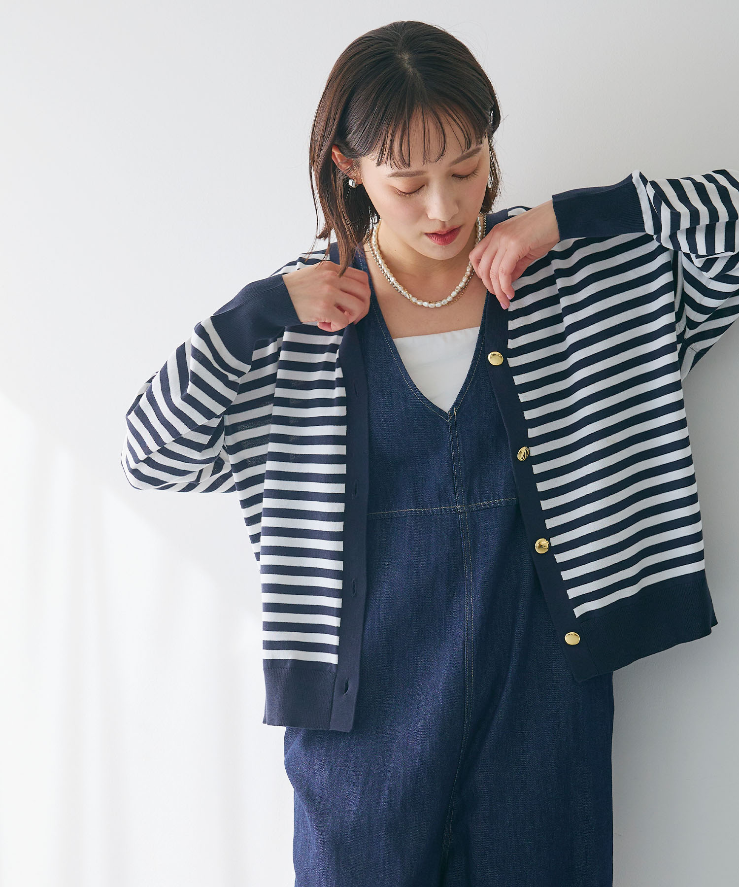 CROSS FUNCTION 金釦ボーダーVネックカーディガンを着用した女性