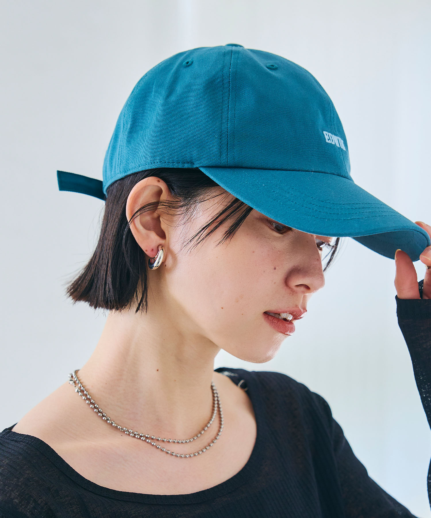 CROSS FUNCTION EDWIN ロゴ刺繍キャップを着用した女性