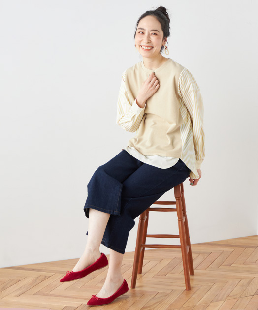 ドッキングプルオーバーを着用して椅子に腰掛け、脚を組んでいる女性の写真