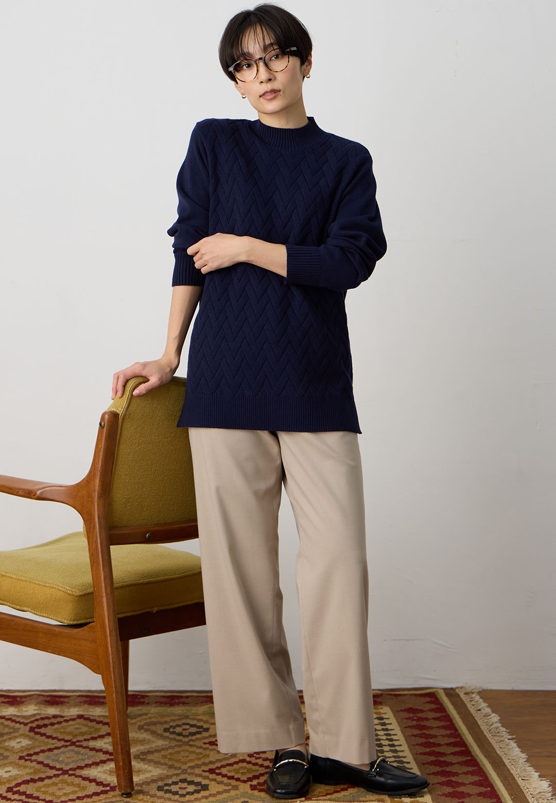 ヘリンボーンニットプルオーバー&裏付きストレートパンツを着用した女性 01