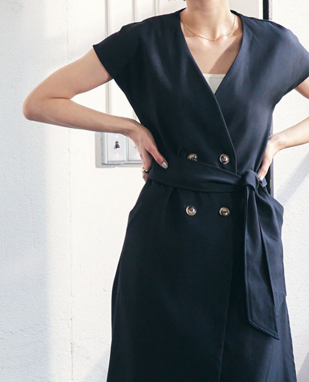 【TOMOコラボ】サイドスリットロングジレベストの黒を着用して腰に手を当てている女性の写真