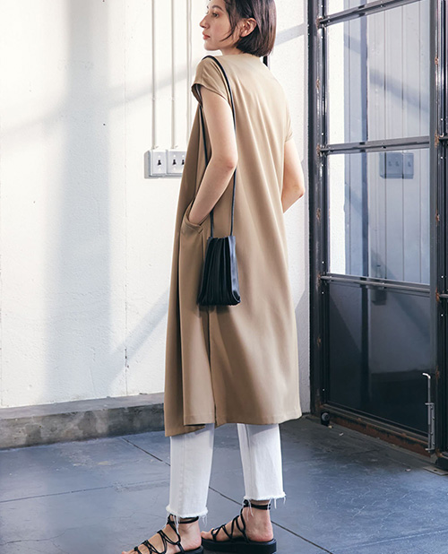 【TOMOコラボ】サイドスリットロングジレベストのベージュを着用して後ろを向いている女性の写真