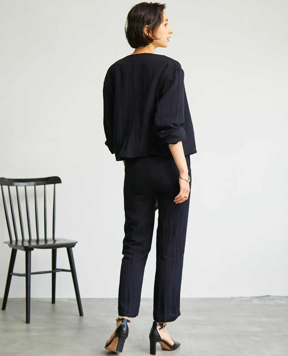 【yun_wearコラボ】ノーカラージャケット＋センターラインピンタック　セットアップの黒を着用して後ろを向いた女性の写真