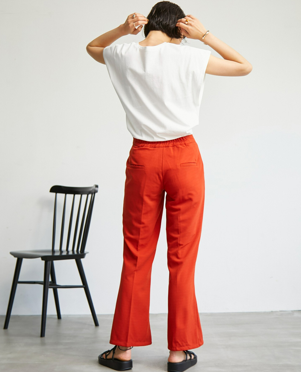 【yun_wearコラボ】サイドスリットカットソーツイルカラーパンツの赤を着用して後ろを向いた女性の写真