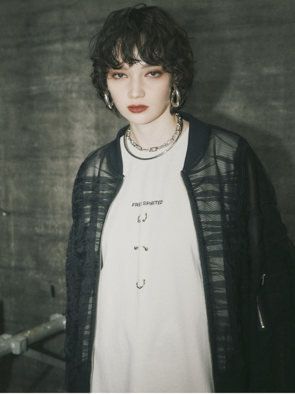 ボディピアスノースリーブTシャツとシャーリングシアーMA-1とダメージクラッシュデニムパンツを着用した女性１