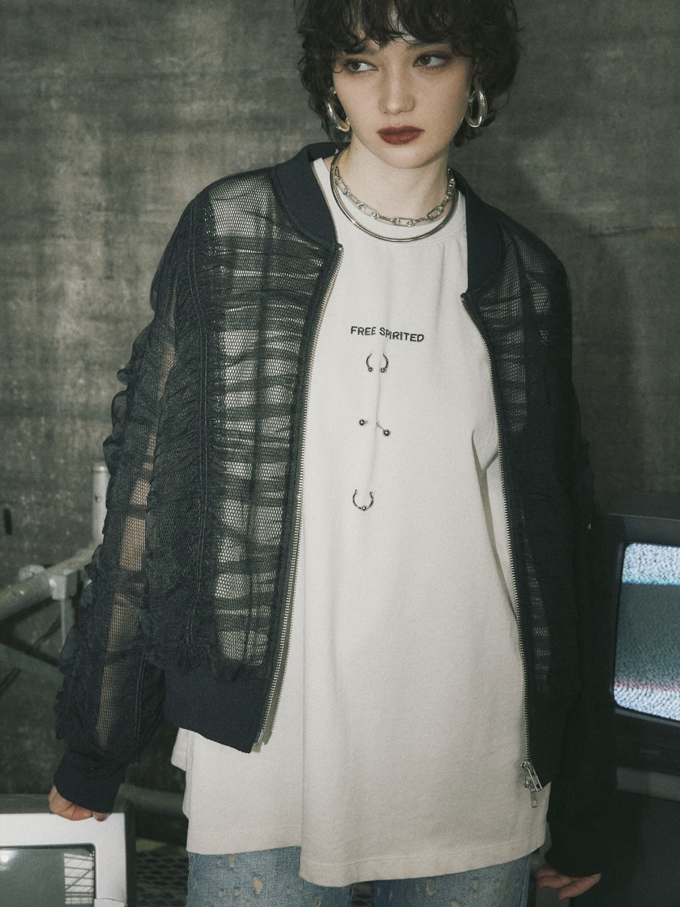 ボディピアスノースリーブTシャツとシャーリングシアーMA-1とダメージクラッシュデニムパンツを着用した女性２