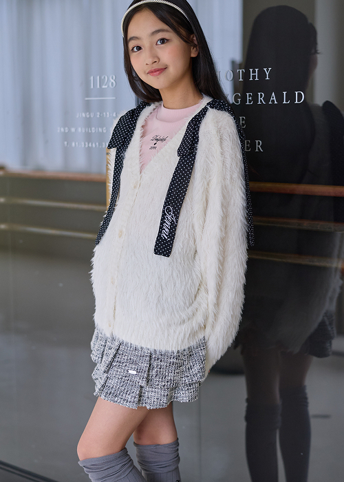 白のファーニットカーディガンにピンクのインナーを合わせた女の子