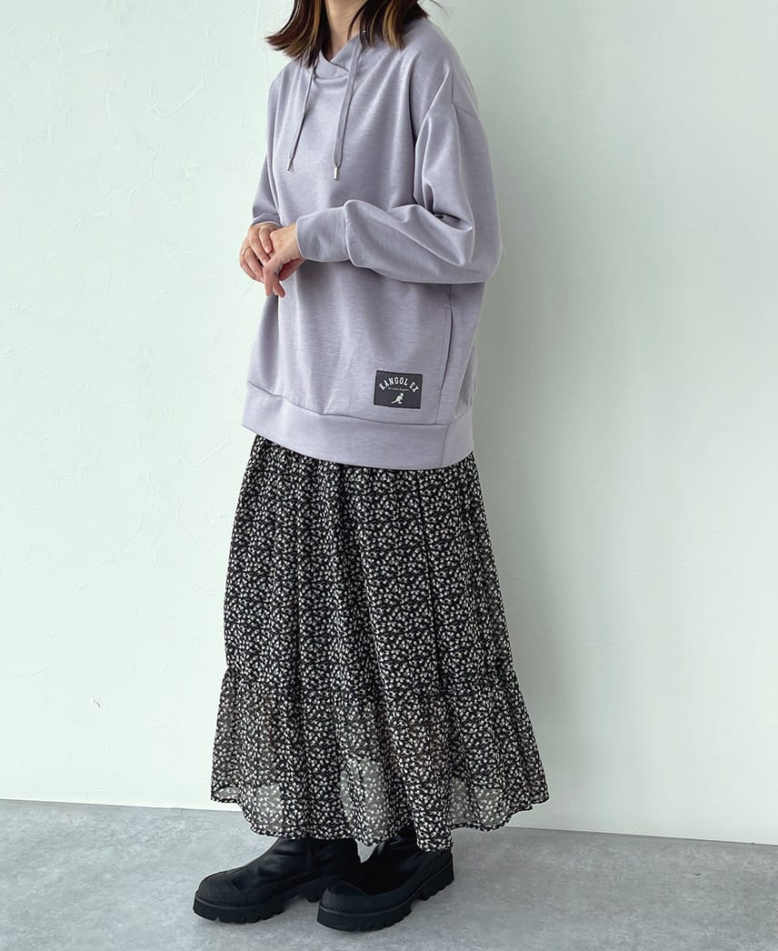 重ね衿パーカー風プルオーバーを着用し、スカートと組み合わせたコーデの女性の写真