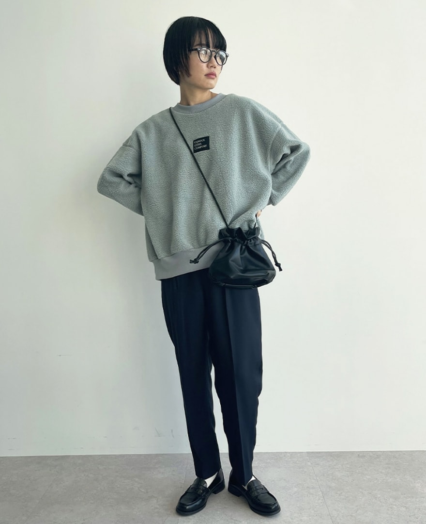 フェルトロゴボアプルオーバーを着用して腰に手を当てている女性の写真