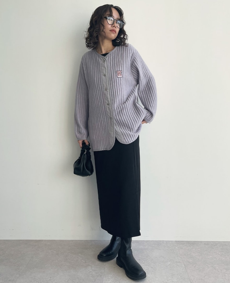タフタ使いキルトジャケットを着用して片手を腰に当てる女性の写真
