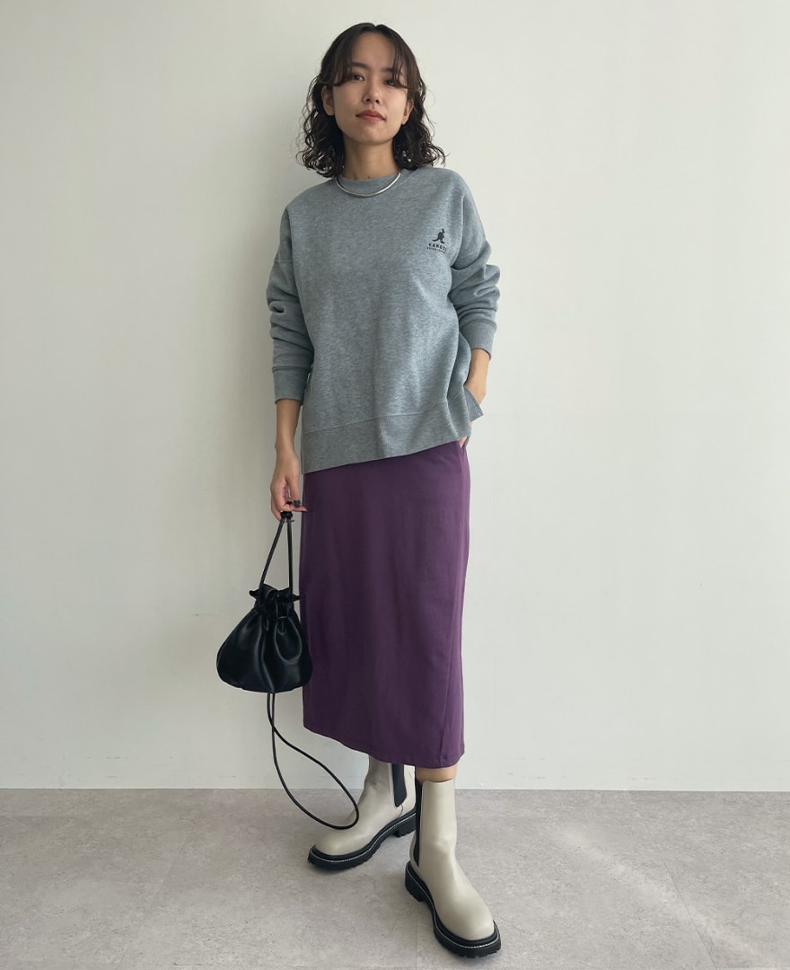 裏起毛胸ポケプルオーバーを着用してスカートのポケットに手を入れている女性の写真