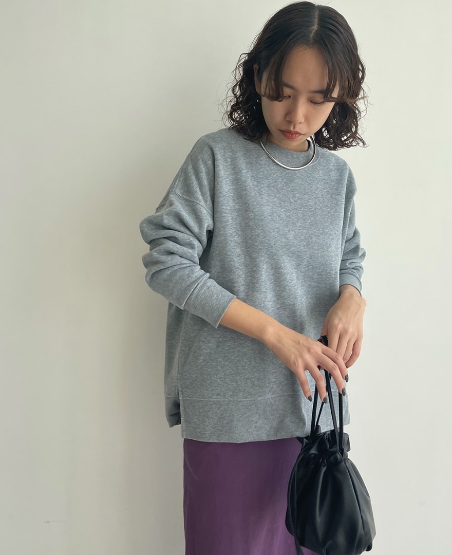 裏起毛胸ポケプルオーバーを着用して袖を捲っている女性の写真