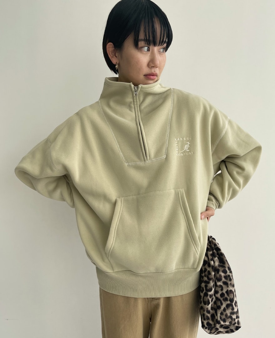 ライトグリーンのセーラーハーフジッププルオーバーを着用して腰に手を当てている女性の写真