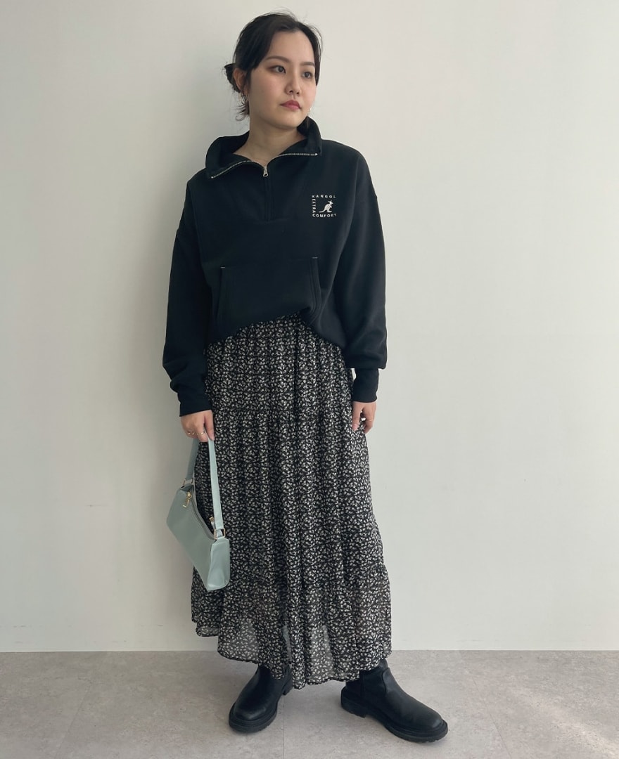 ブラックのセーラーハーフジッププルオーバーを着用して立っている女性の写真