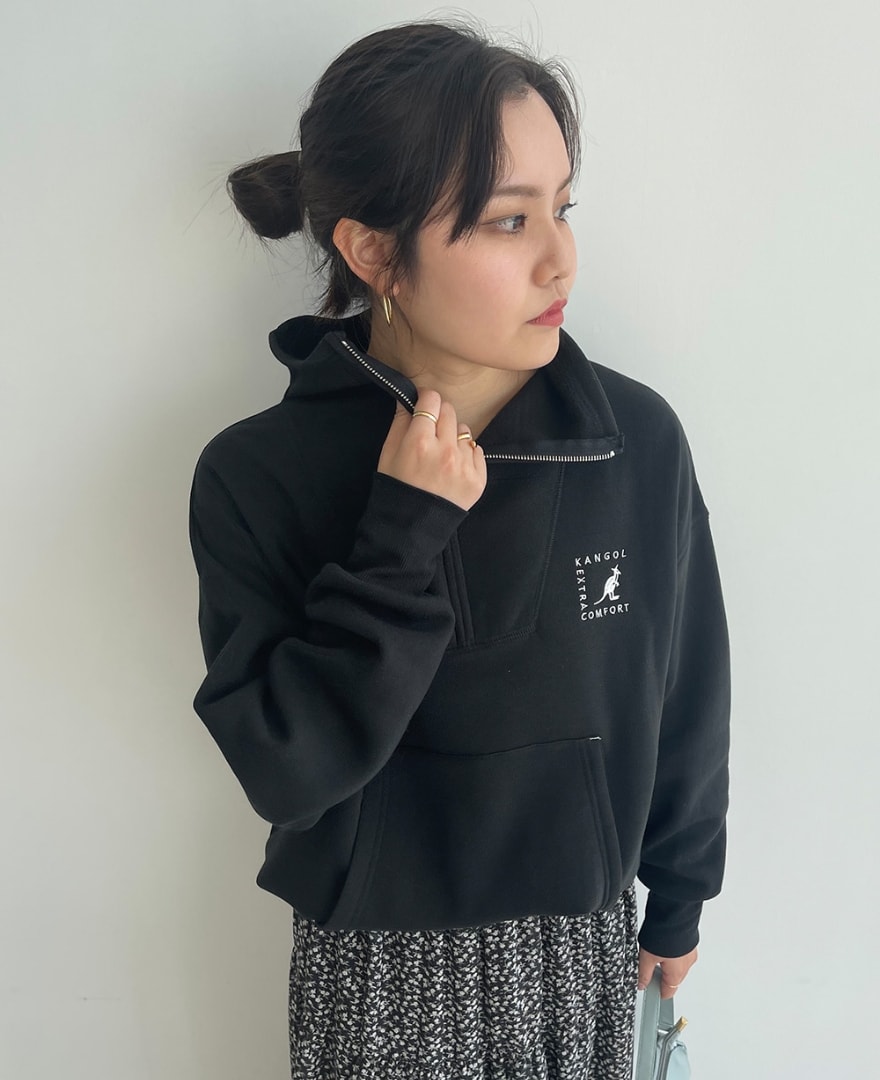 ブラックのセーラーハーフジッププルオーバーを着用して襟元に手を添えている女性の写真