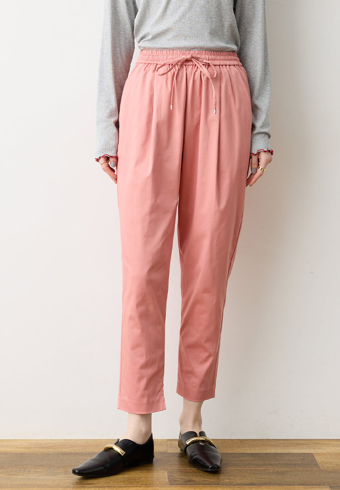 コーラルピンク色のストレッチタックテーパードパンツの着用イメージ