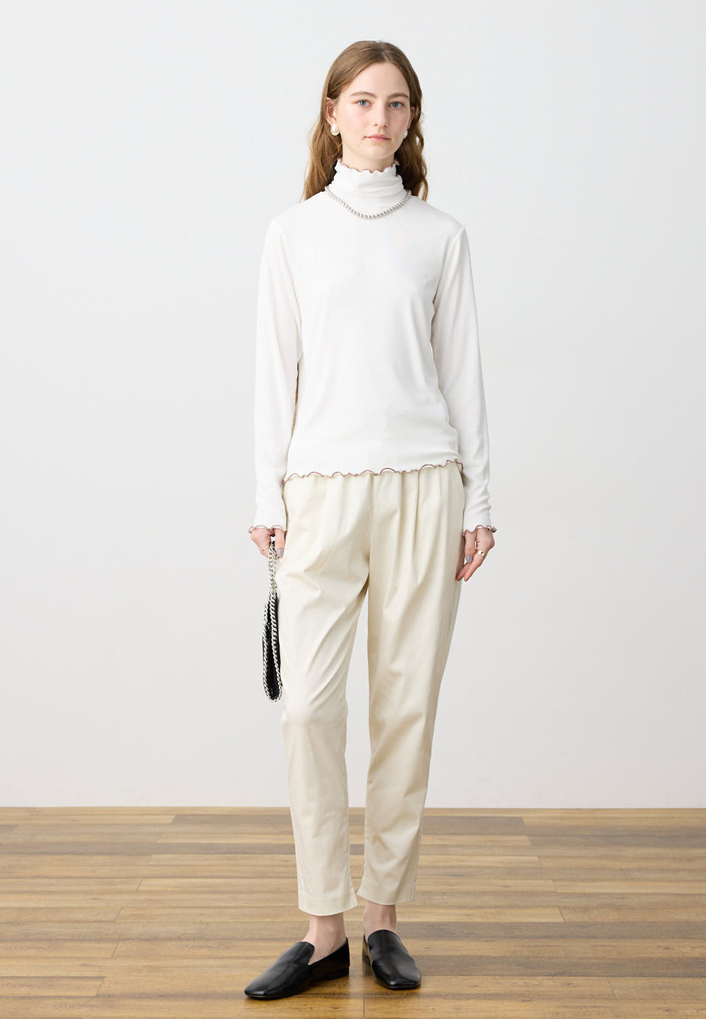 バイカラーメローハイネックプルオーバー、ストレッチタックテーパードパンツを着用した女性の画像