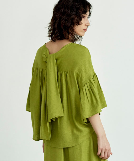 リネン混ショルダープリーツタックブラウスを着用している女性の写真