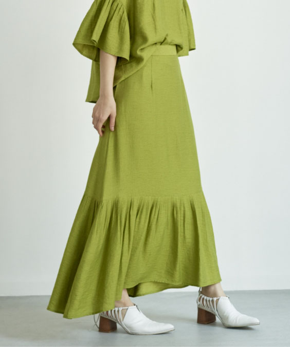 リネン混プリーツテールカットスカートを着用している女性の写真