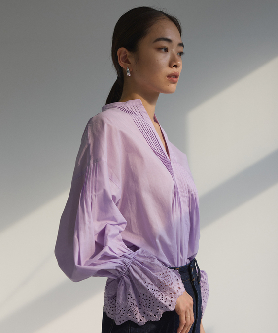 カットワーク刺繍ブラウスのライラックを着用している女性の写真