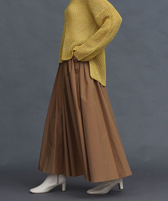ランダムタックフレアースカートのラキャメルを着用している女性の写真