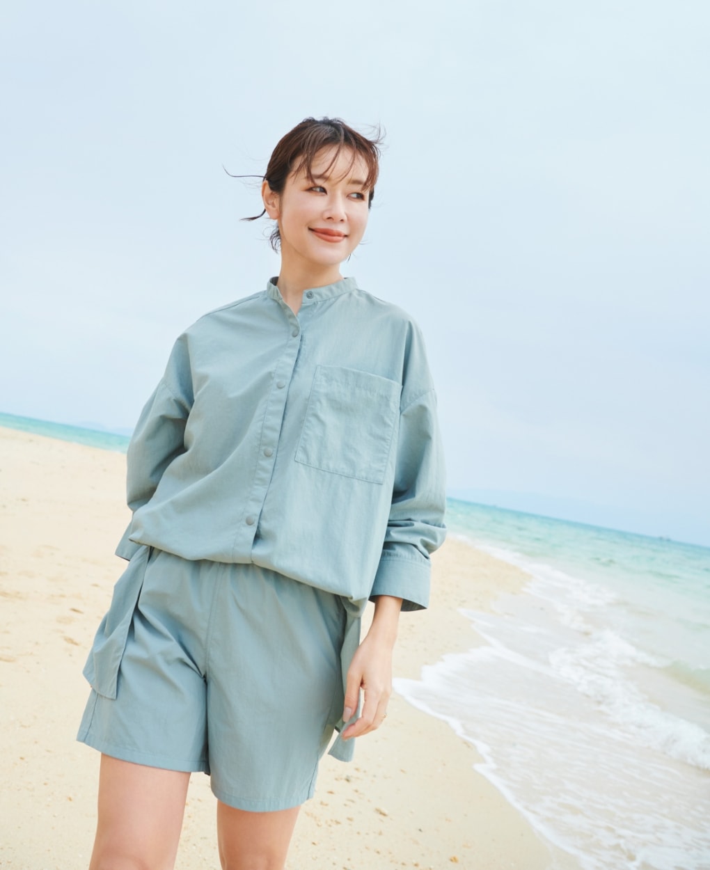 ラッシュガードショートパンツとラッシュガードシャツを着用した女性が浜辺を歩いている写真