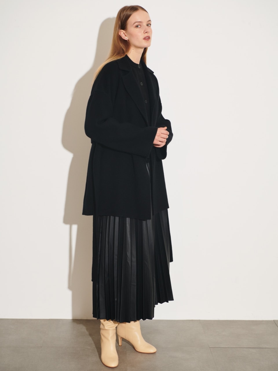 ベルテッドミドル丈リバーコート（ブラック）を着用した女性の全身の写真