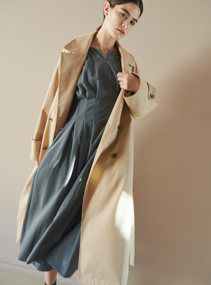 ベージュのロングダブルコート、グレーのウォッシャブルタックワンピースを着用している女性の写真