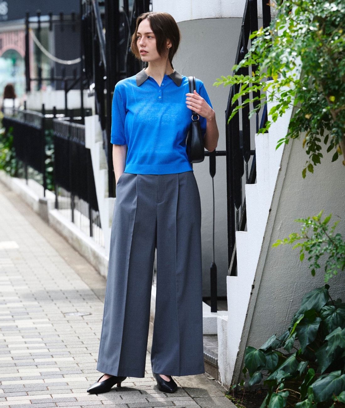 ニットポロシャツとパンツとバッグを着用した女性３