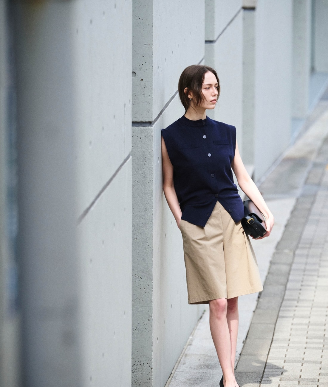 ニットベストとパンツとバッグを着用した女性３
