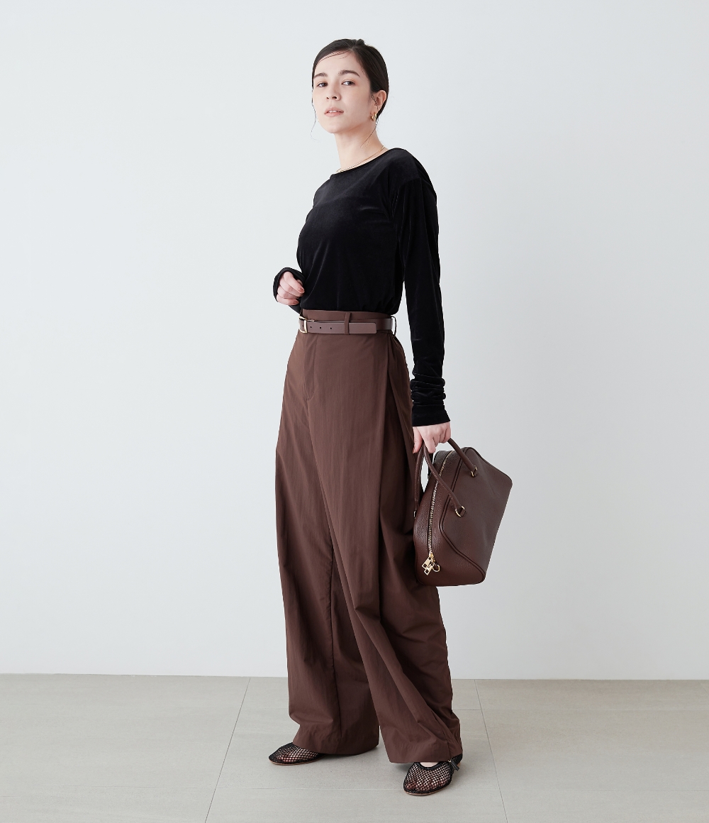 ブラックのベロアトップスとチョコレートカラーのバレルパンツを着用した女性の画像--2