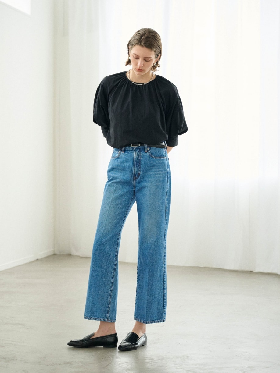 ブラウスとデニムとネックレスとピアスを着用した女性