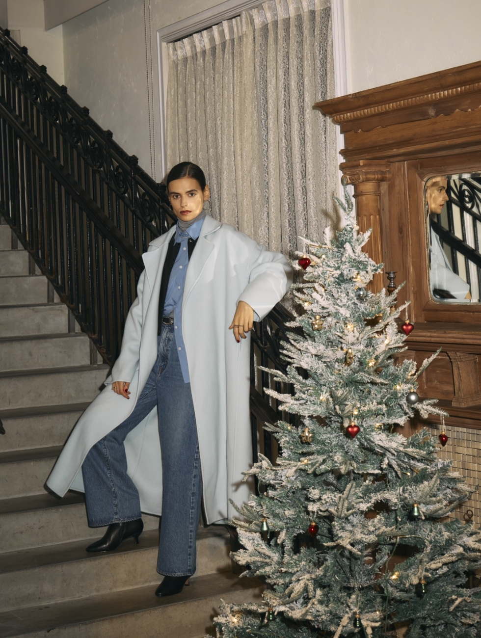 アイスブルーのウールメルトンロングリバーコート・黒のフェイクレザーショートジャケット・ブルーのコンフォータブルシャツ・グレーのメリノウールシアータートル・ミッドブルーの【NEEDBY】ANNIEのフレアデニムを着用した女性が階段上でポーズをとるビジュアル。