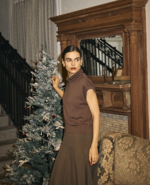 シルクコットンオフタートルニットとウォッシャブルマチフレアスカート【CLEAN MOTION】を着用して、クリスマスツリーの傍に立つ女性のビジュアル