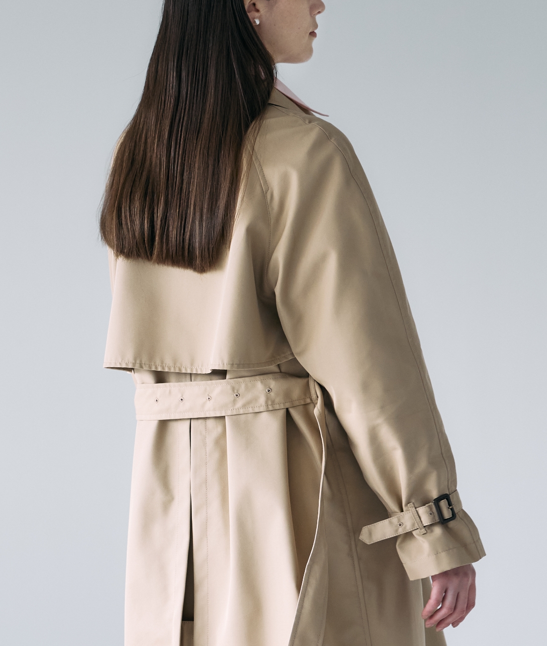 ベージュのロングトレンチコートを着用した女性の後ろ姿の画像