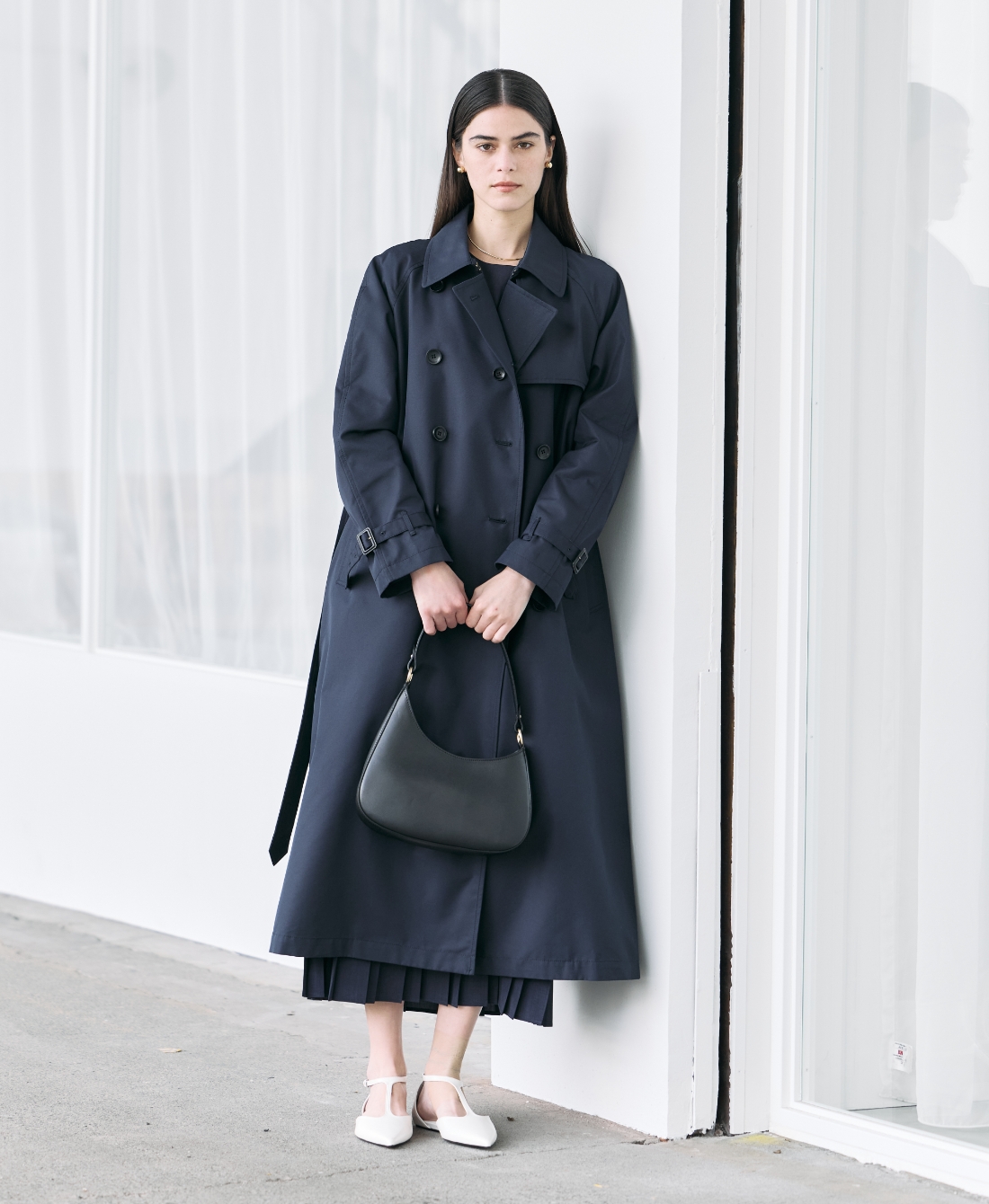 ネイビーのロングトレンチコート・ブラックのトップス・ブラックのスカートを着用した女性の画像--1