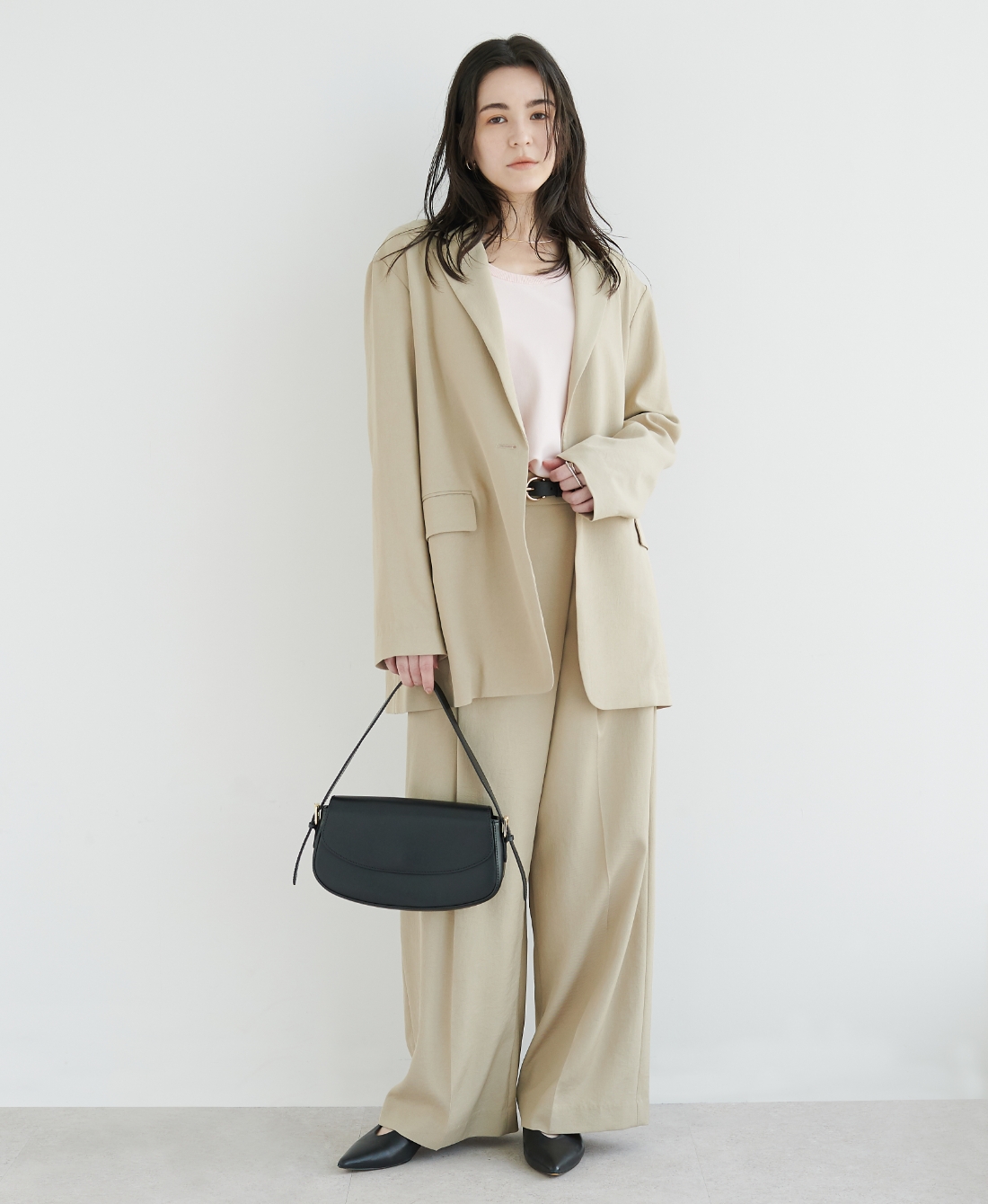ベージュの【トリアセリネン】テーラードジャケット・パステルピンクのニット・ベージュの【トリアセリネン】ラップトラウザーパンツ・ブラックのバッグを着用した女性の画像--1