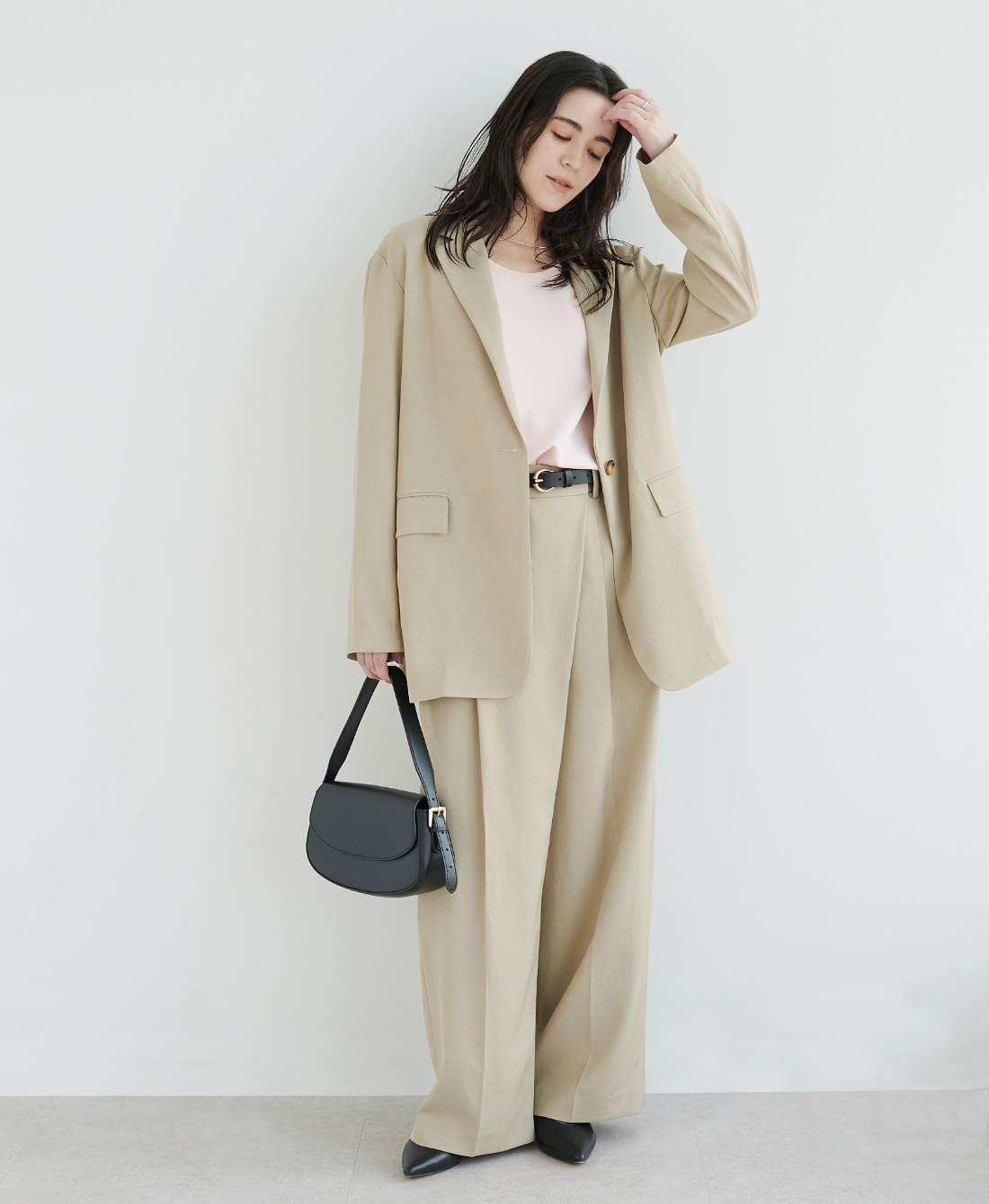 ベージュの【トリアセリネン】テーラードジャケット・パステルピンクのニット・ベージュの【トリアセリネン】ラップトラウザーパンツ・ブラックのバッグを着用した女性の画像--2