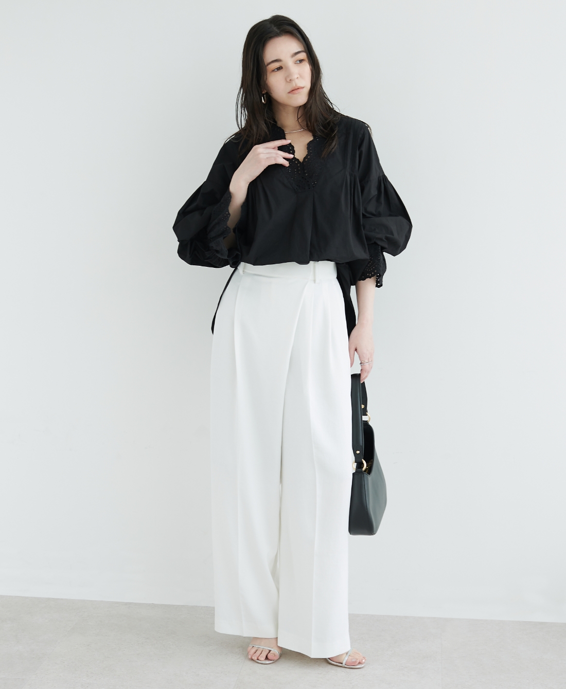 ブラックのブラウス・ホワイトの【トリアセリネン】ラップトラウザーパンツ・ブラックのバッグを着用した女性の画像--1