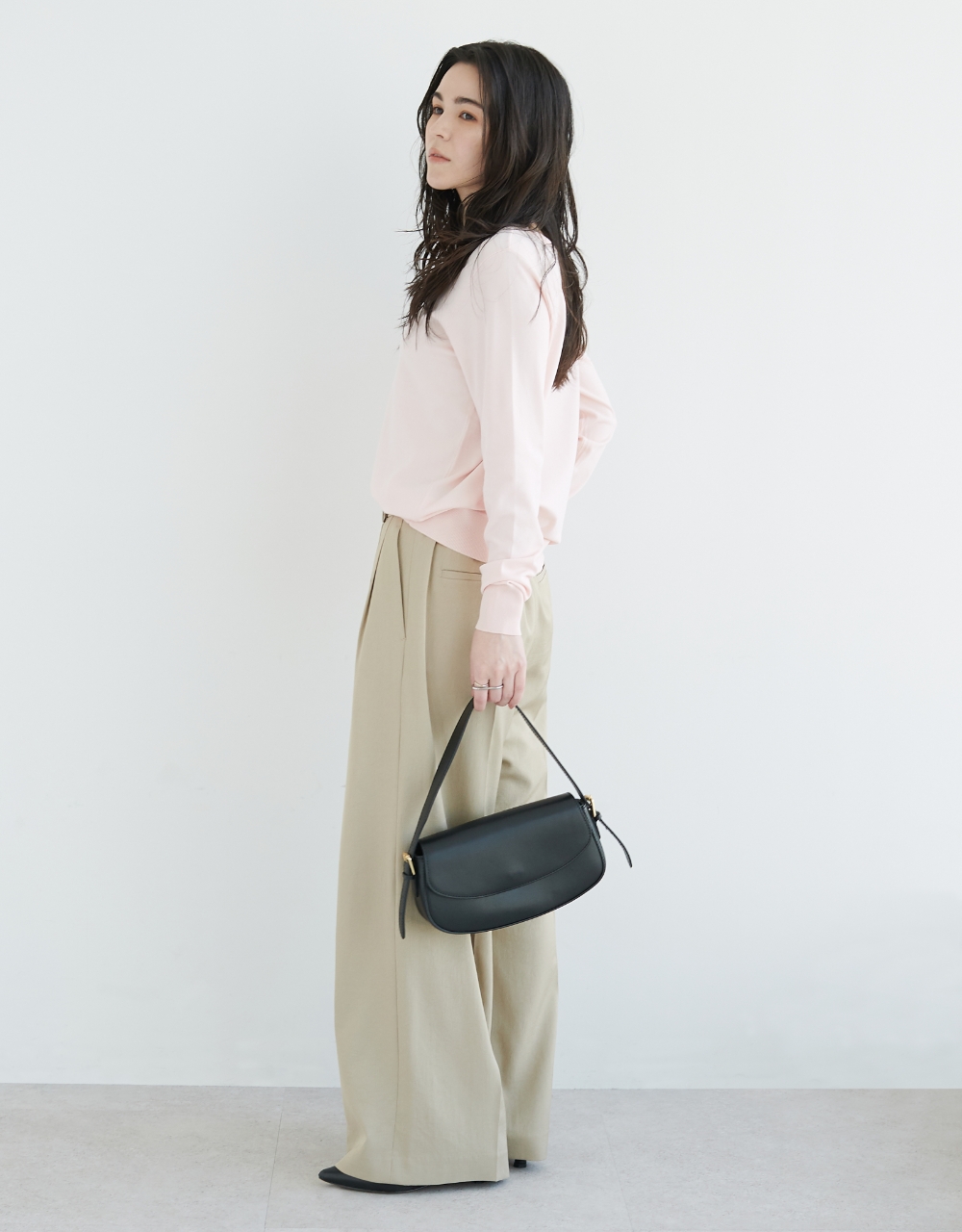 パステルピンクのニット・ベージュの【トリアセリネン】ラップトラウザーパンツ・ブラックのバッグを着用している女性の画像--1