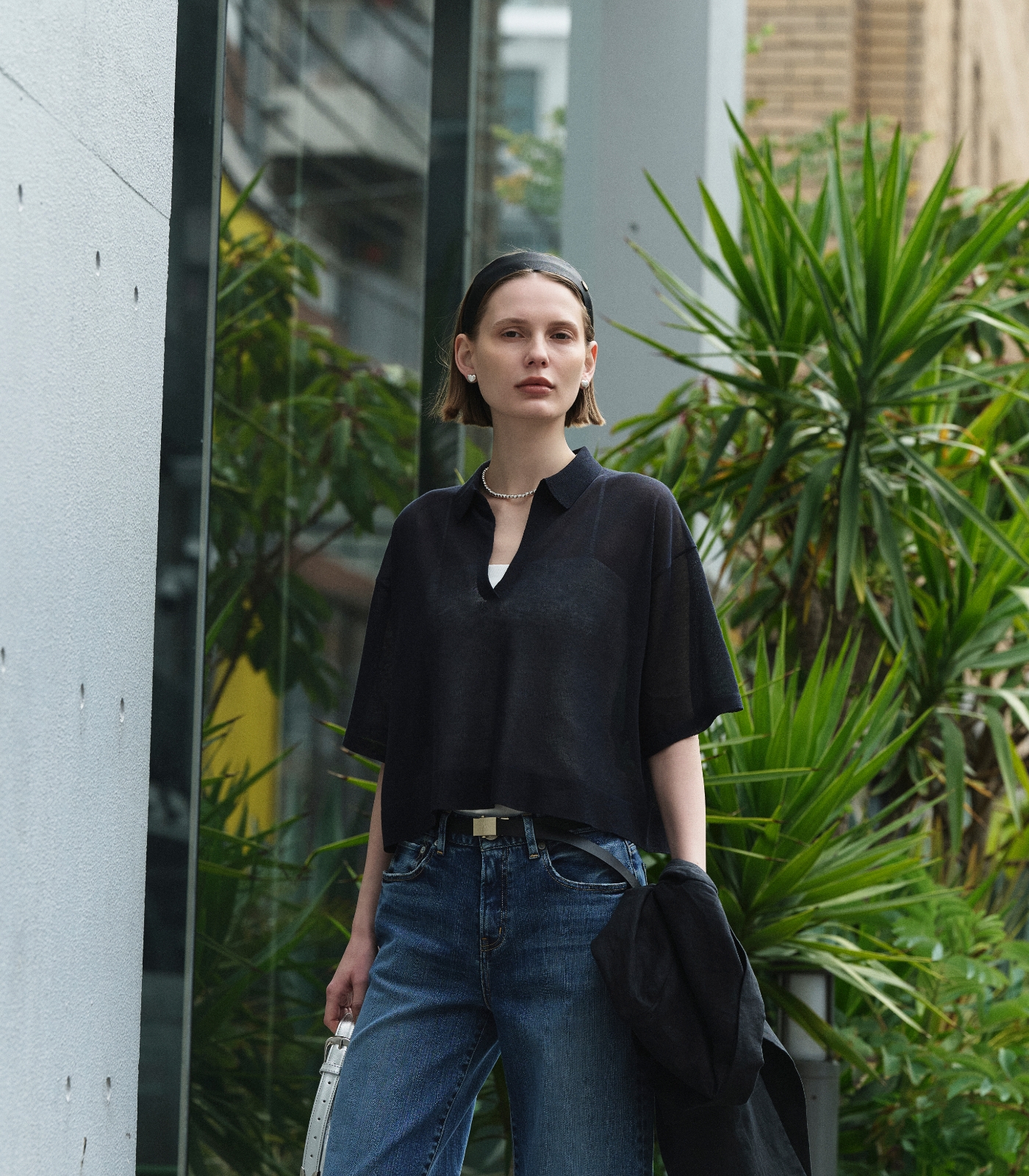 黒いジャケットとニット、デニムパンツを着用した女性１