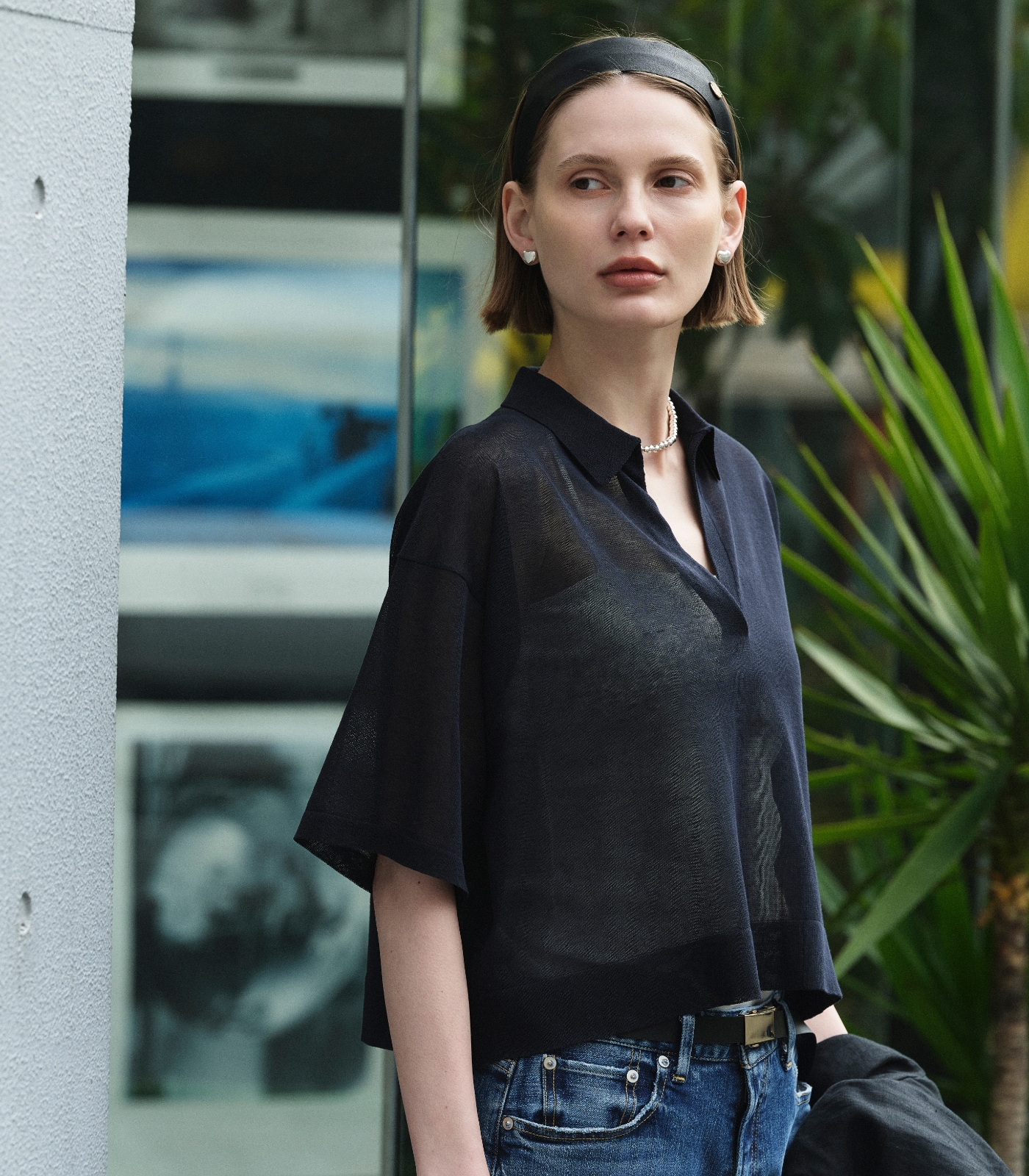 黒いジャケットとニット、デニムパンツを着用した女性２