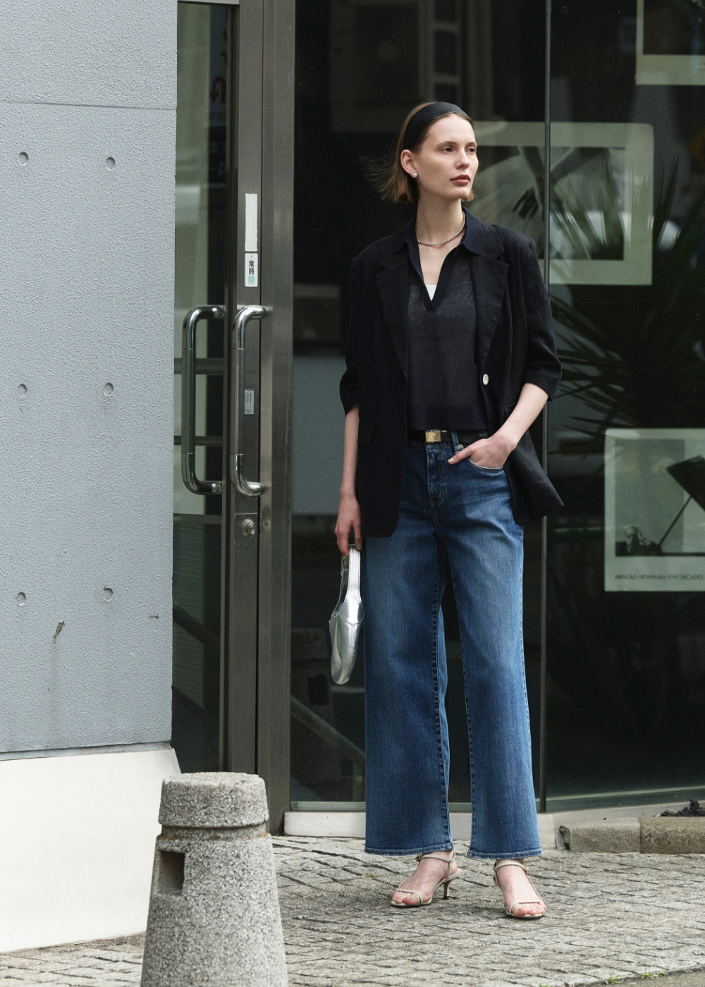 黒いジャケットとニット、デニムパンツを着用した女性３