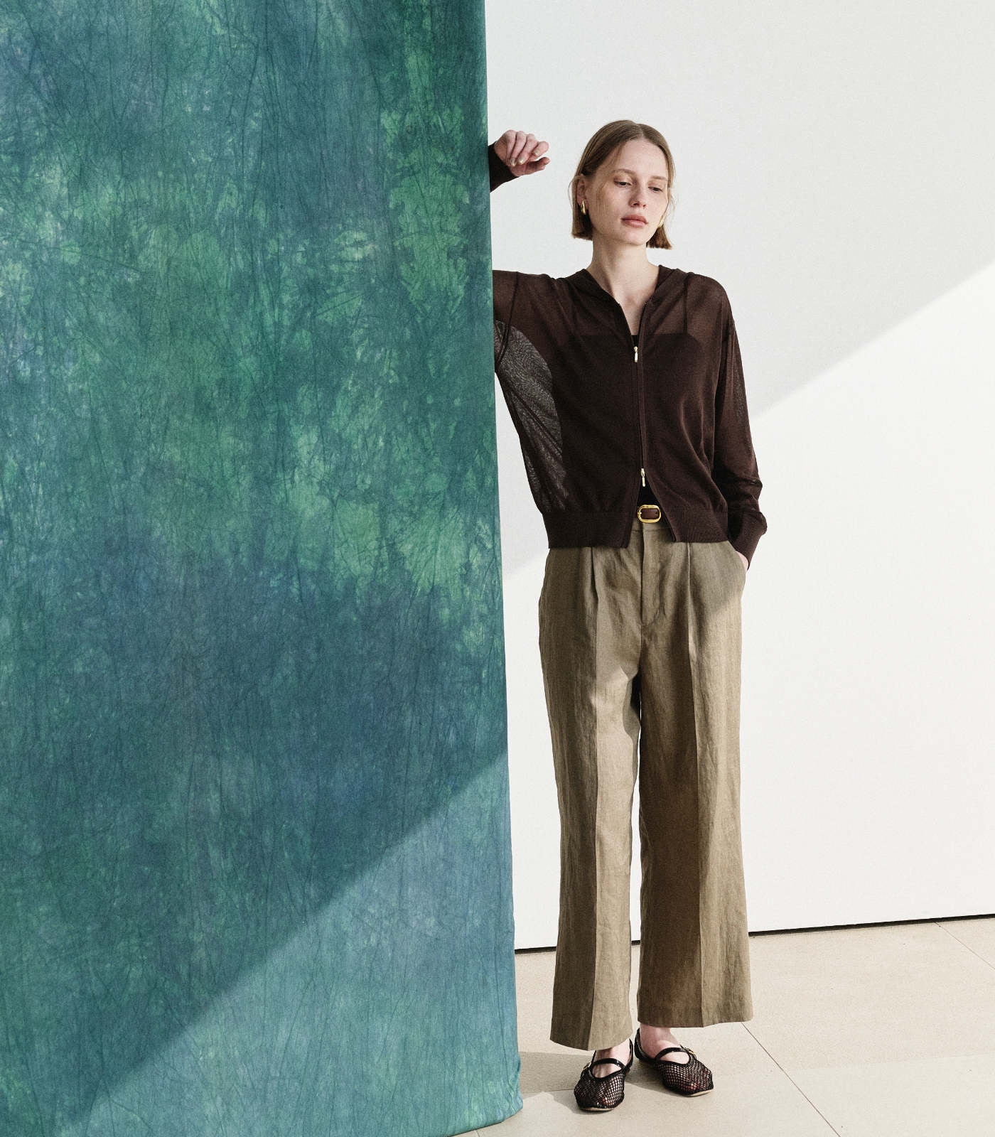 ブラウン色のニットフーディーとストレートパンツを着用した女性１