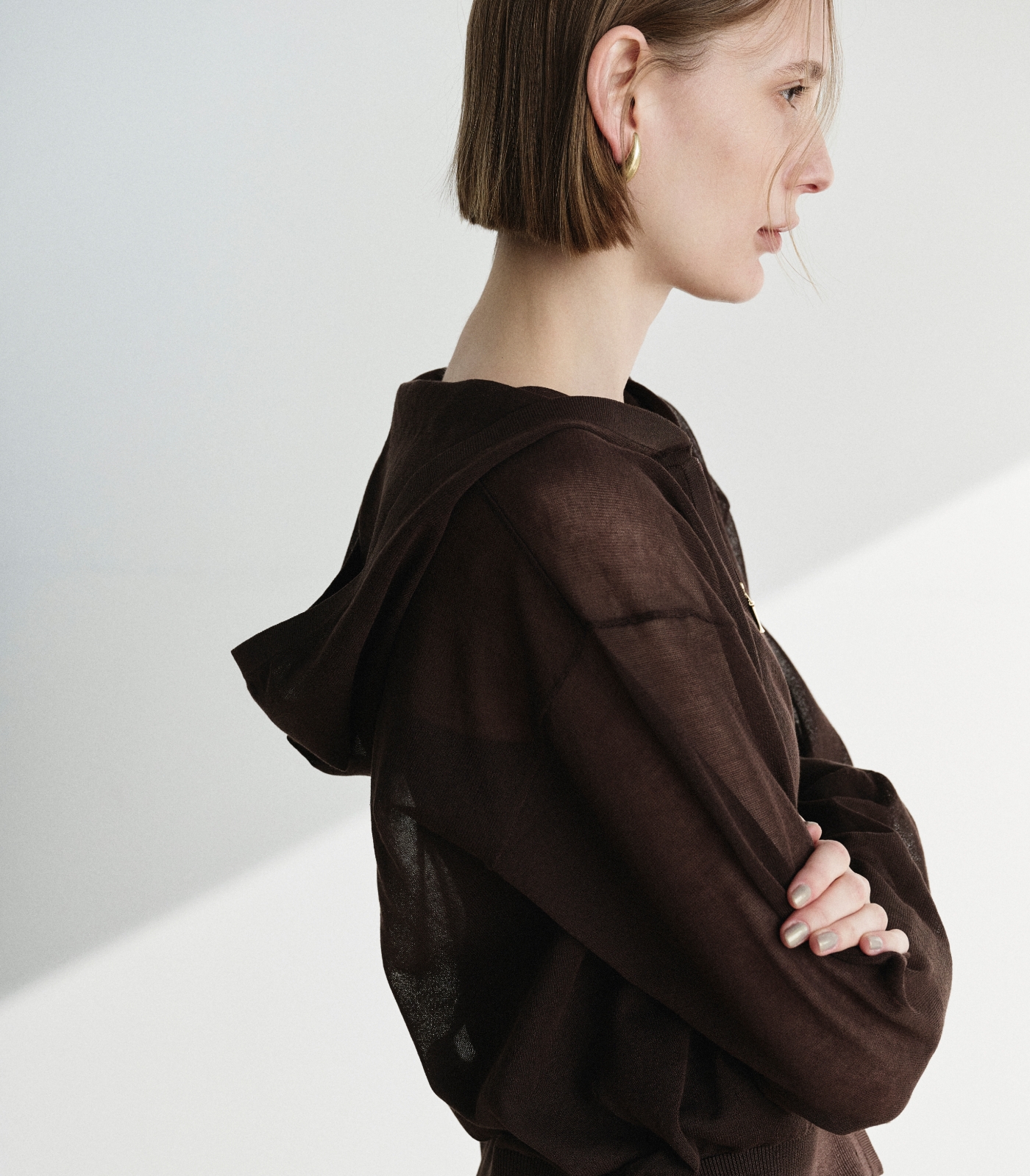 ブラウン色のニットフーディーとストレートパンツを着用した女性２