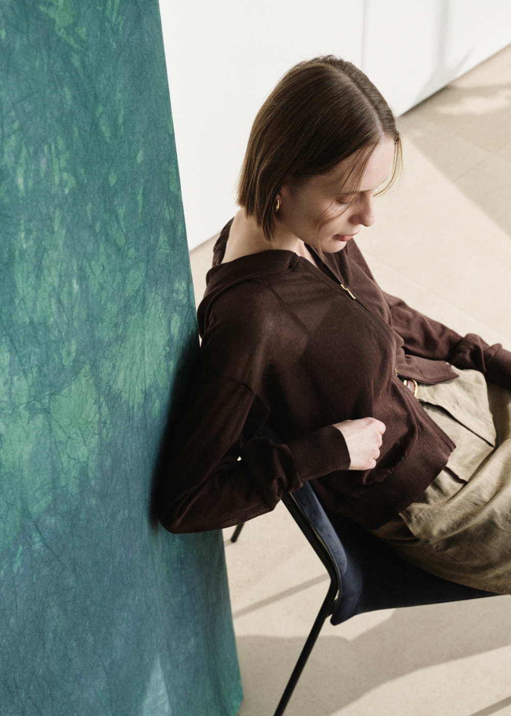 ブラウン色のニットフーディーとストレートパンツを着用した女性３